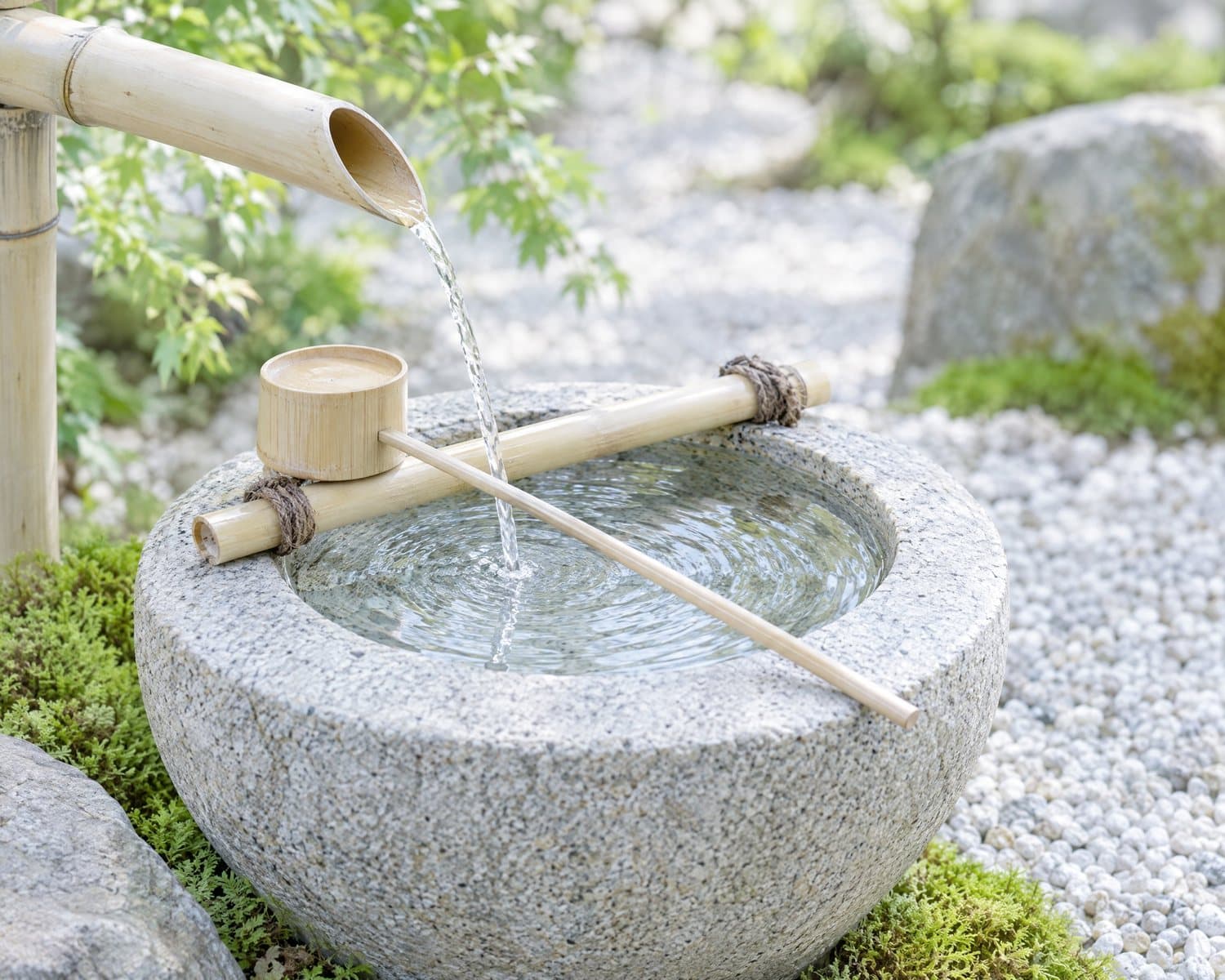 Water running from a bamboo spout into a stone basin