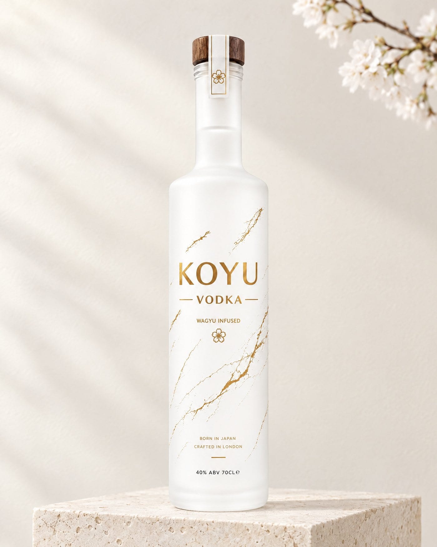 KOYU Vodka: a tall white frosted glass bottle printed in gold, standing on white marble in soft daylight